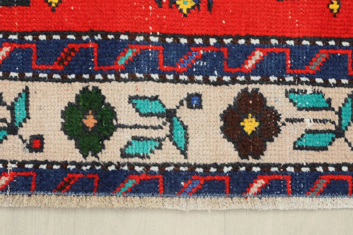 Close-up of the beige border with stylized floral and leaf motifs in green, red, and brown