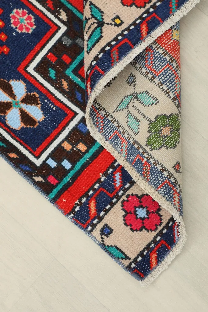 Corner of the rug folded to reveal the backside and the cotton foundation