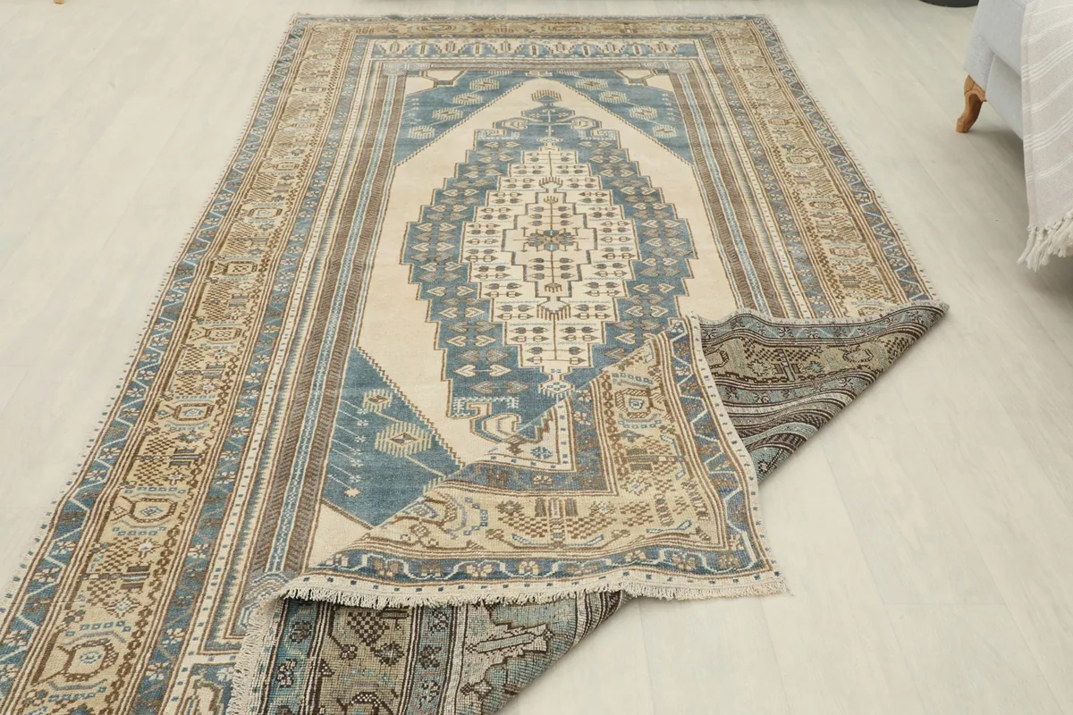 The vintage rug partially folded to show the thickness and texture of the wool pile.