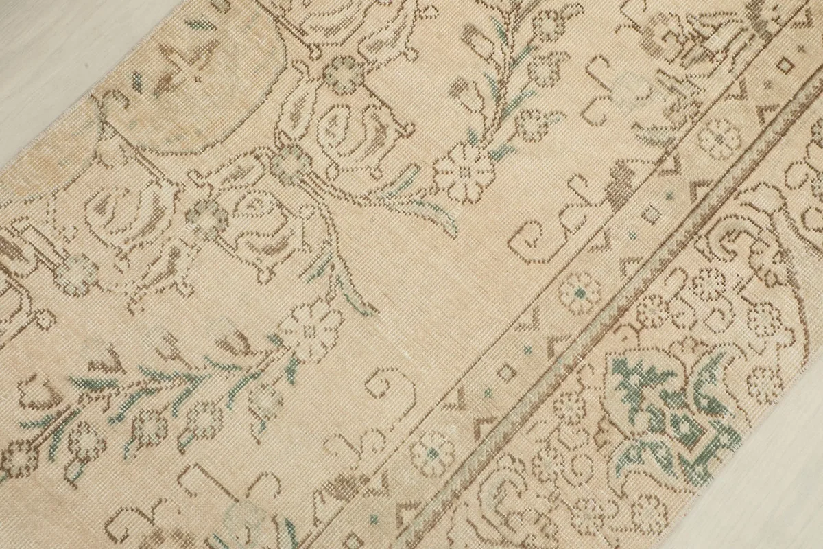 Detailed view of the rug's central design, revealing the faded botanical elements and border details.
