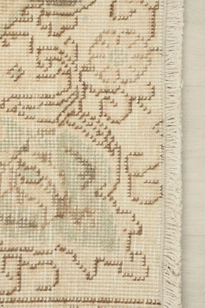 Close-up of the rug's fringe and the intricate hand-knotted pattern at the edge.