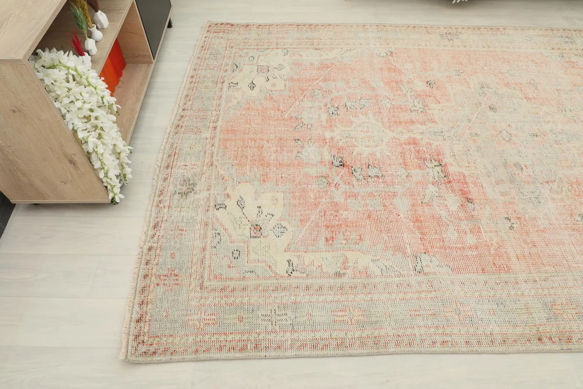 Detailed angle of the rug's surface, highlighting the faded rose field and light gray border elements