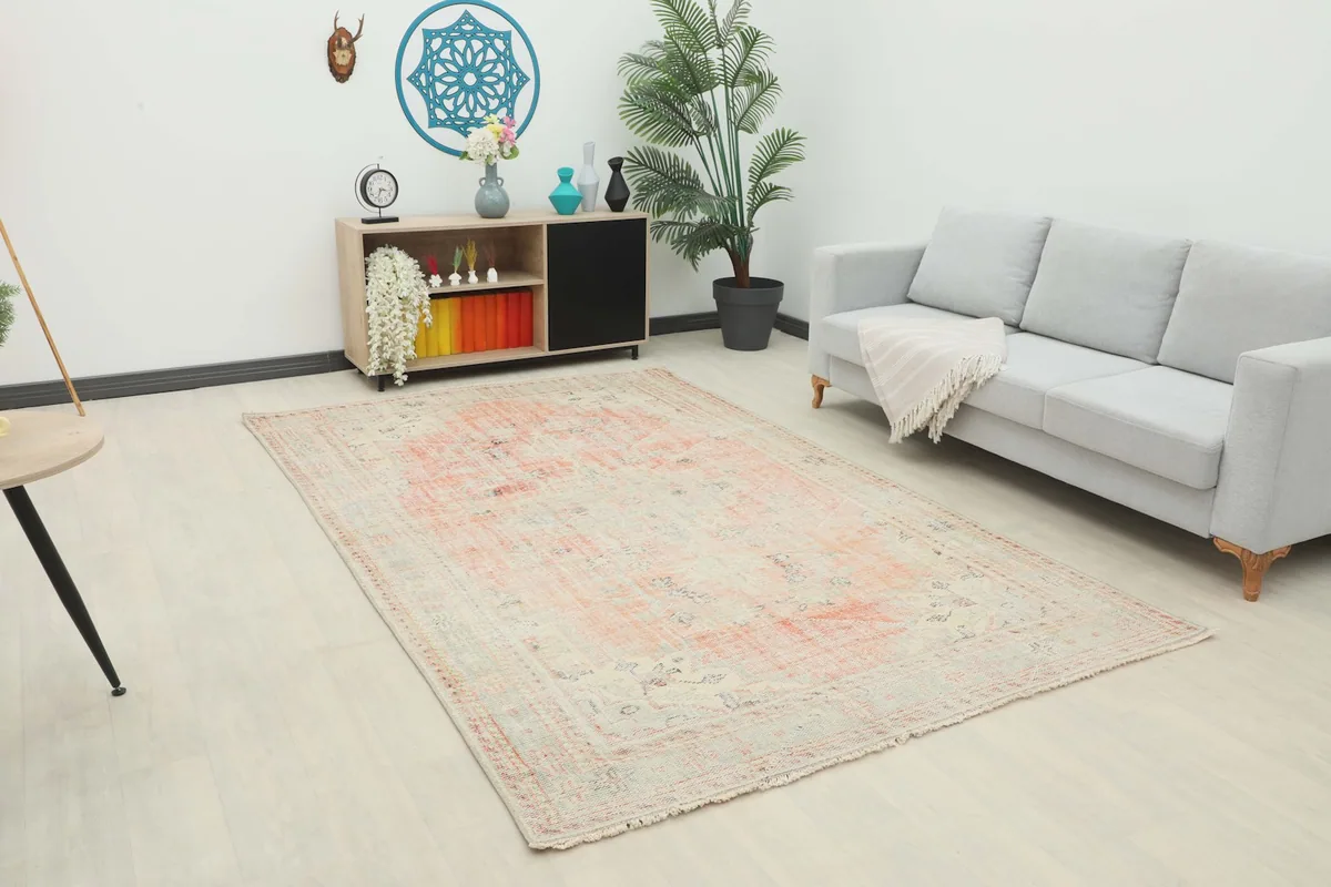 Vintage rose area rug displayed in a living room setting with a light gray sofa and wooden furniture