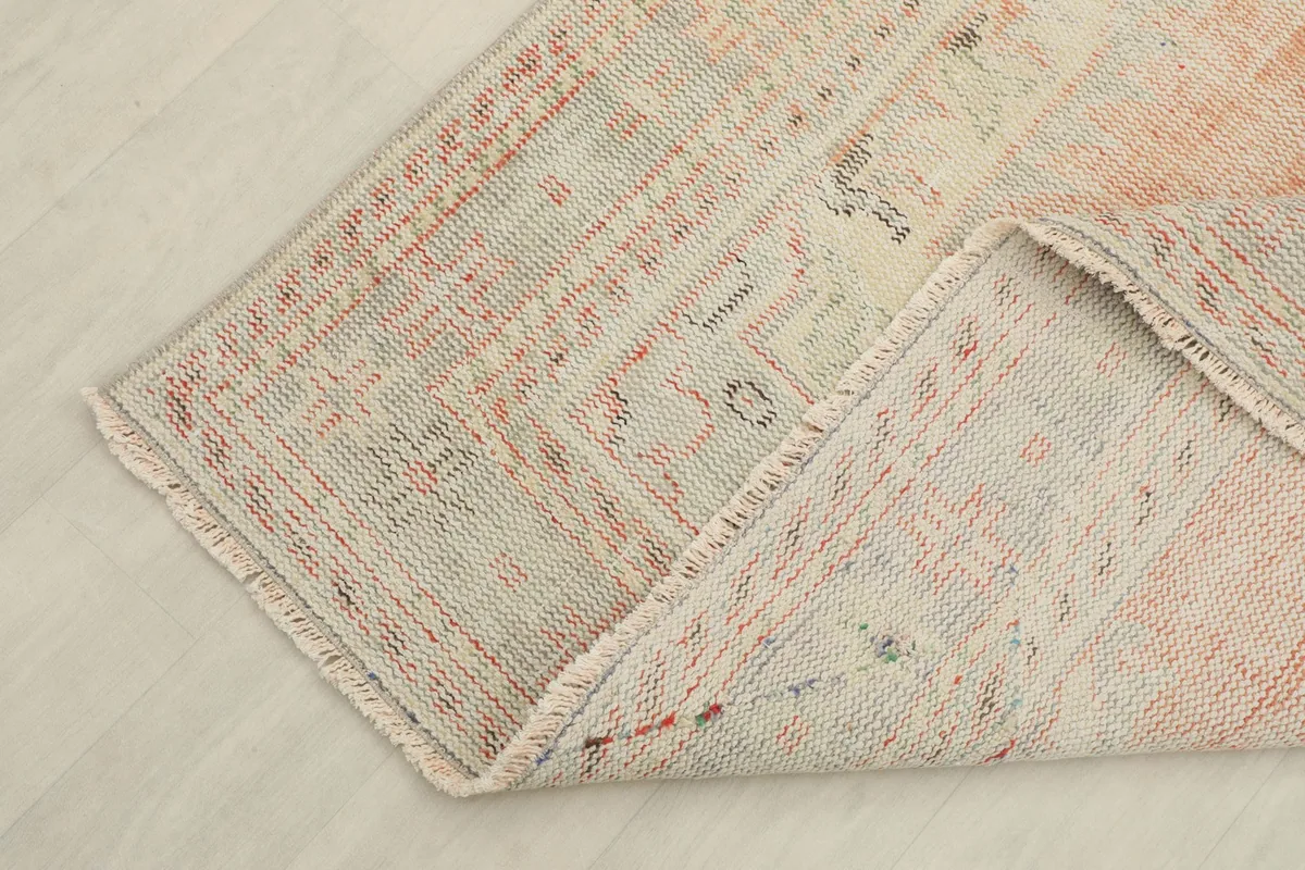 Corner of the rug folded back to reveal the tight weave and a glimpse of the cotton foundation