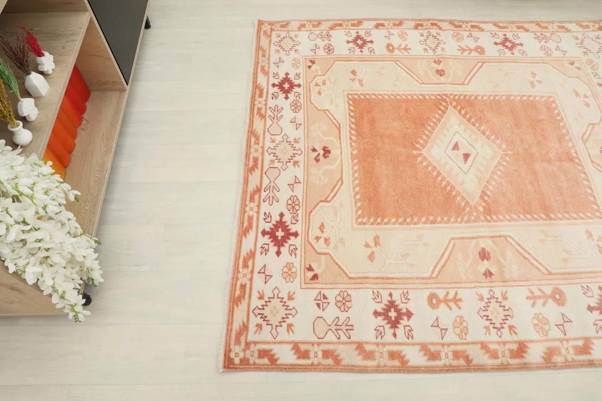 Overhead angle view of the rug, highlighting the central orange medallion and cream border