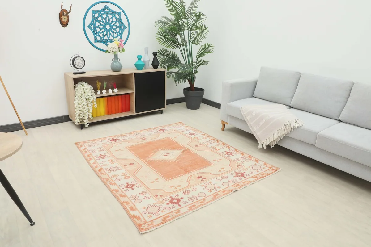 Vintage orange and cream rug placed in a modern living room setting next to a gray sofa