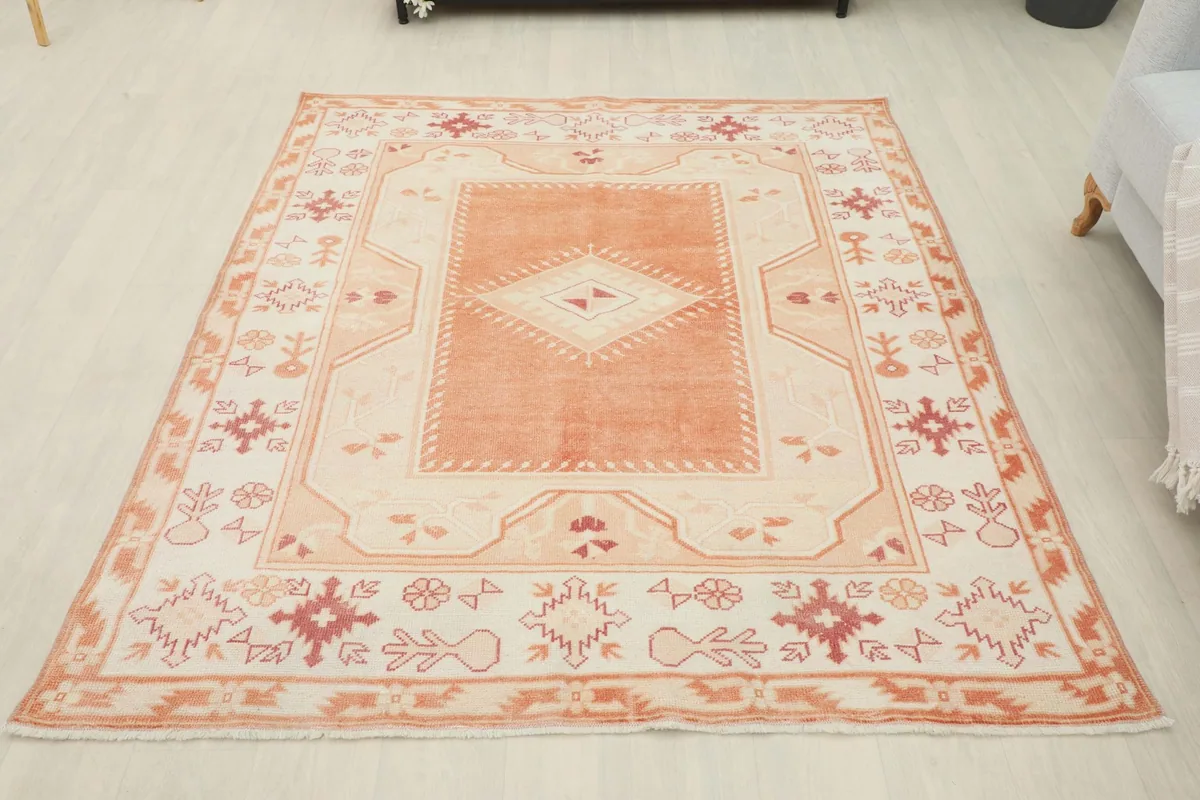 Full overhead view of the vintage orange and cream rug in a room setting