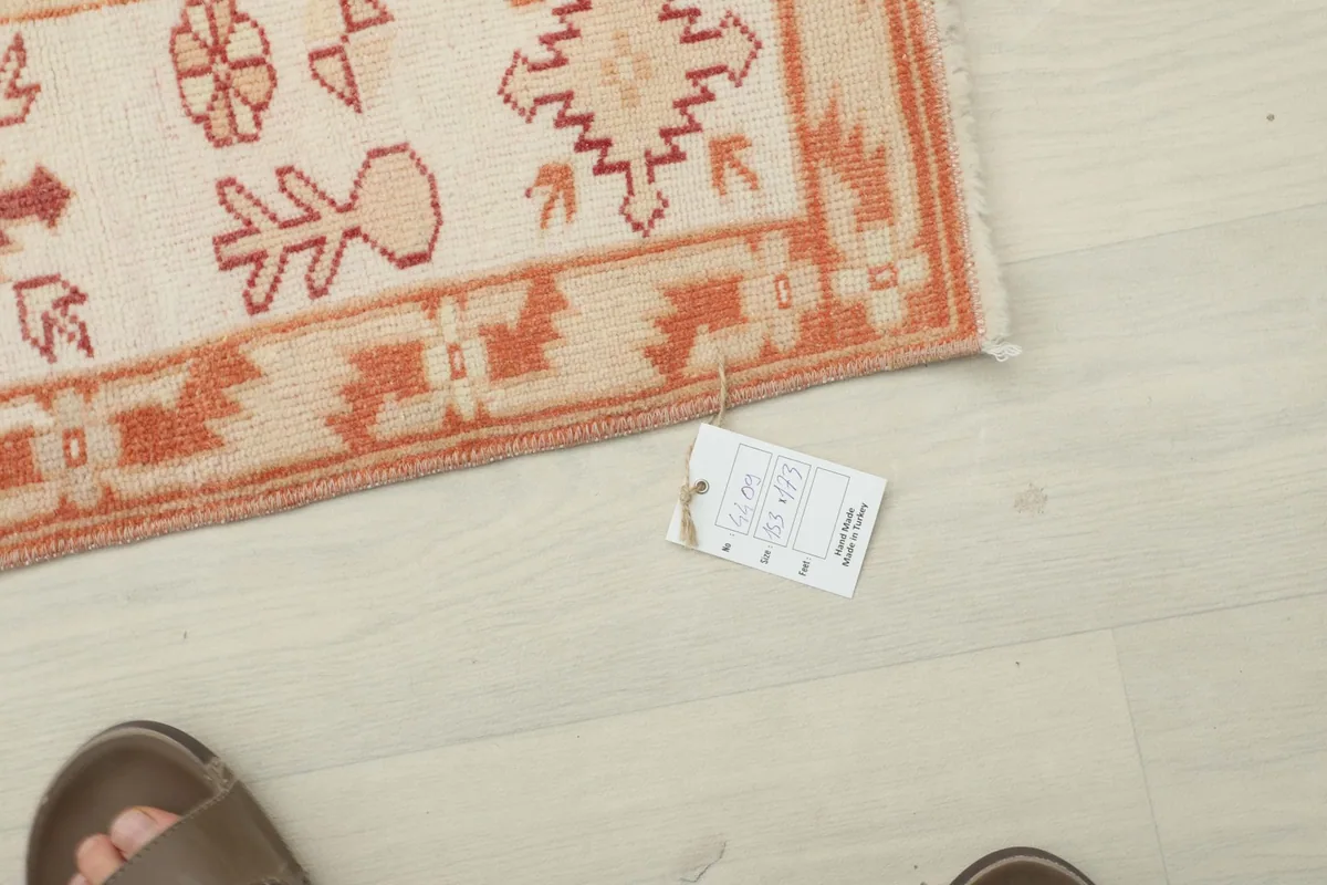 Overhead view showing a tag attached to the rug's edge, with a person's foot nearby for scale