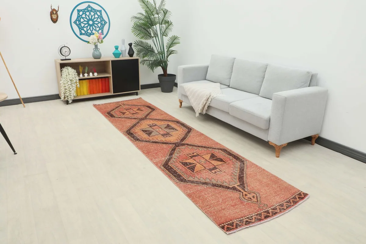 Rust geometric runner rug laid out in a modern living space with a light gray sofa and decorative shelving.