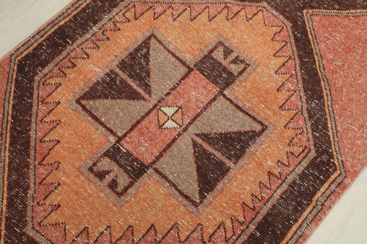 Detailed shot of a central geometric medallion featuring brown, orange, and beige tones with intricate lines.