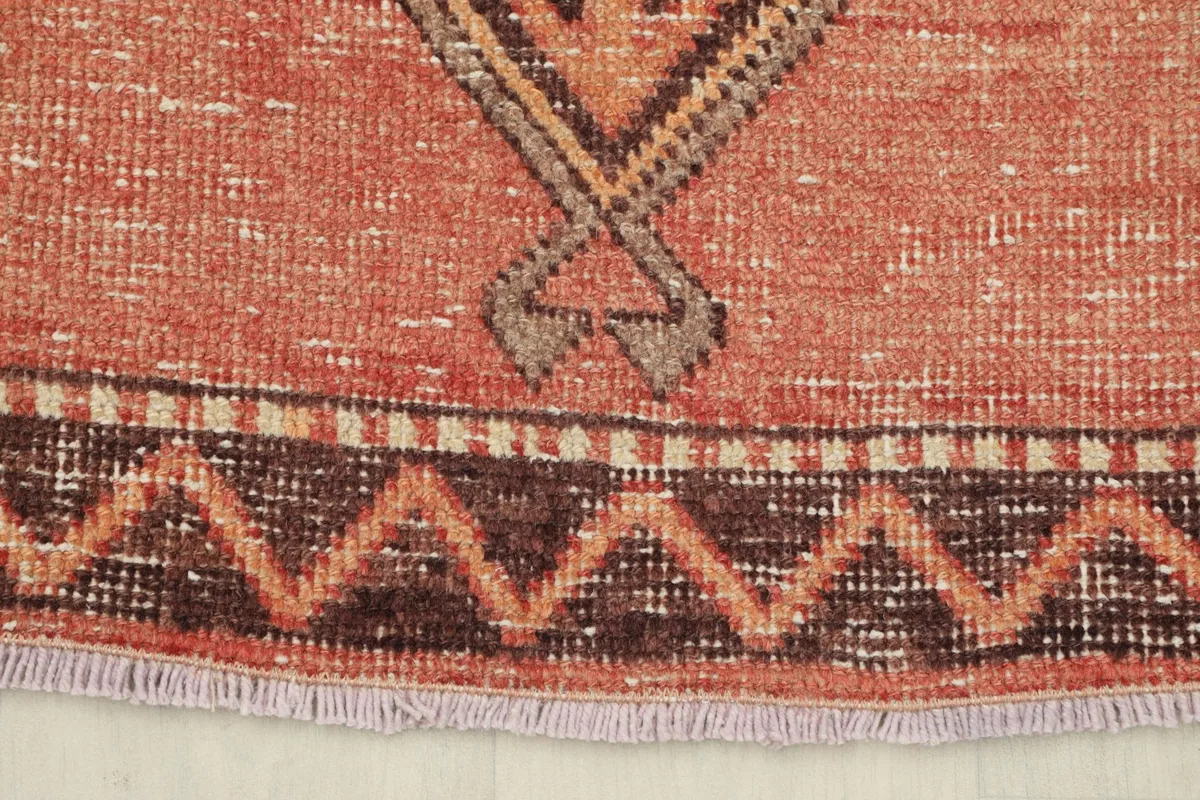 Close-up of the rug's end, showing the short, natural fringes and the distinct border pattern.