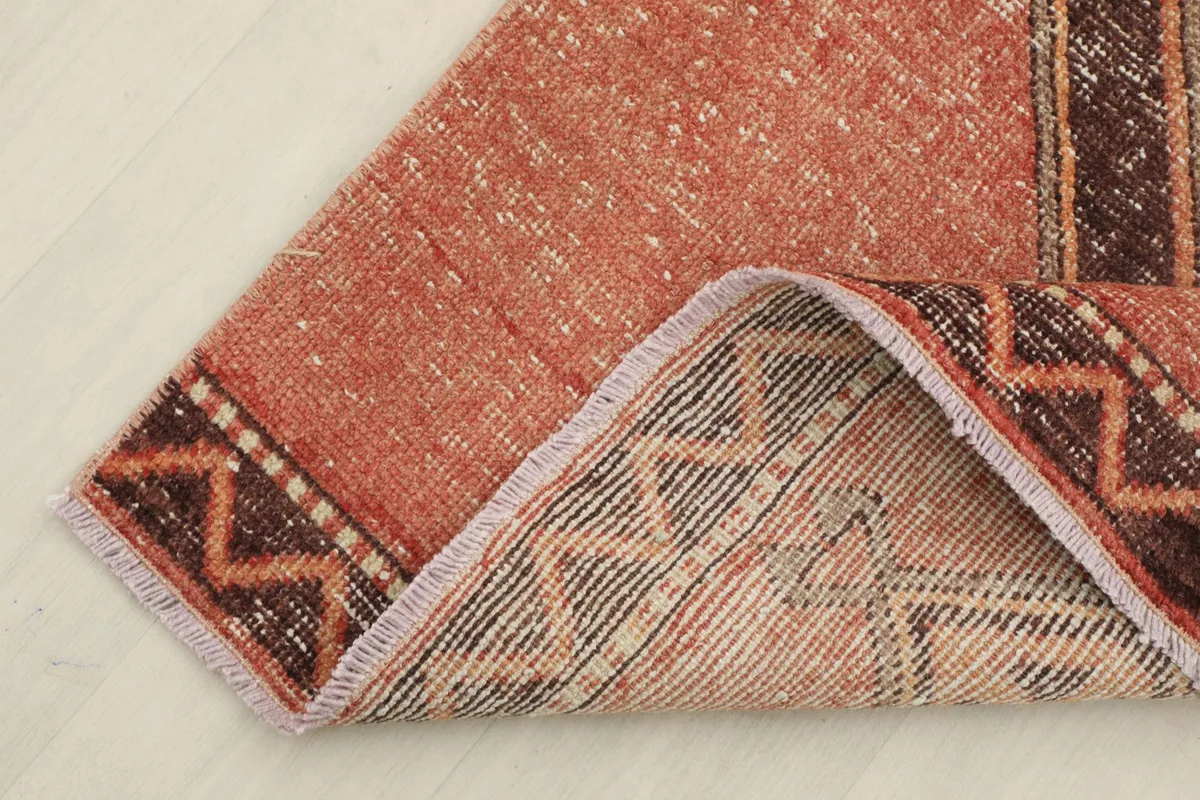 Corner of the rug folded back to reveal the cotton foundation and the reverse side of the hand-knotting.