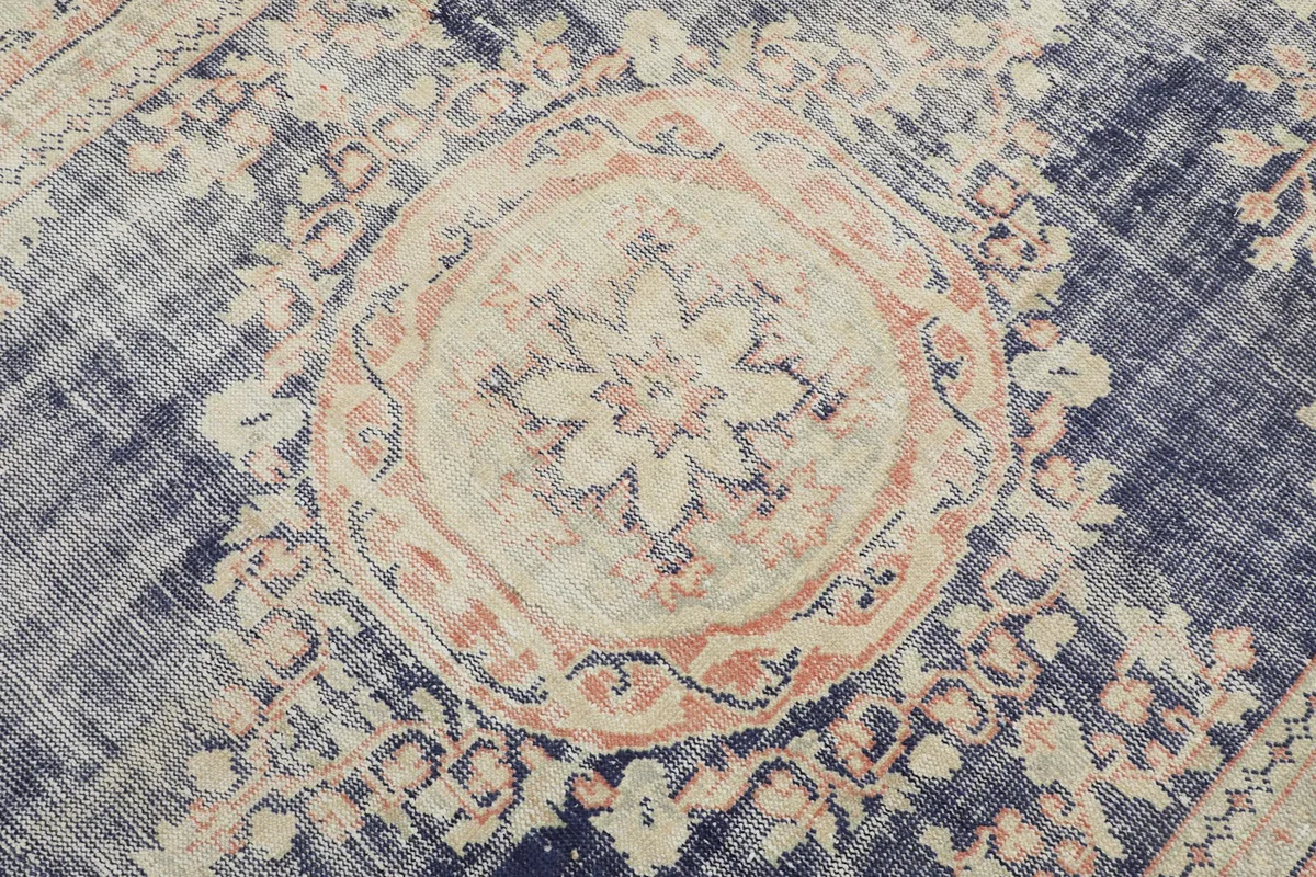 Detail shot of the central medallion with floral motifs in rose and beige against the navy field.