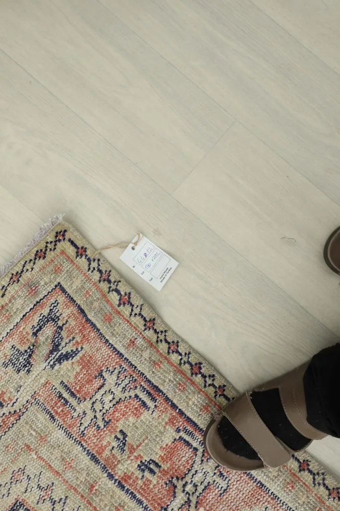 Tag on the rug corner, with a person's foot nearby for scale.