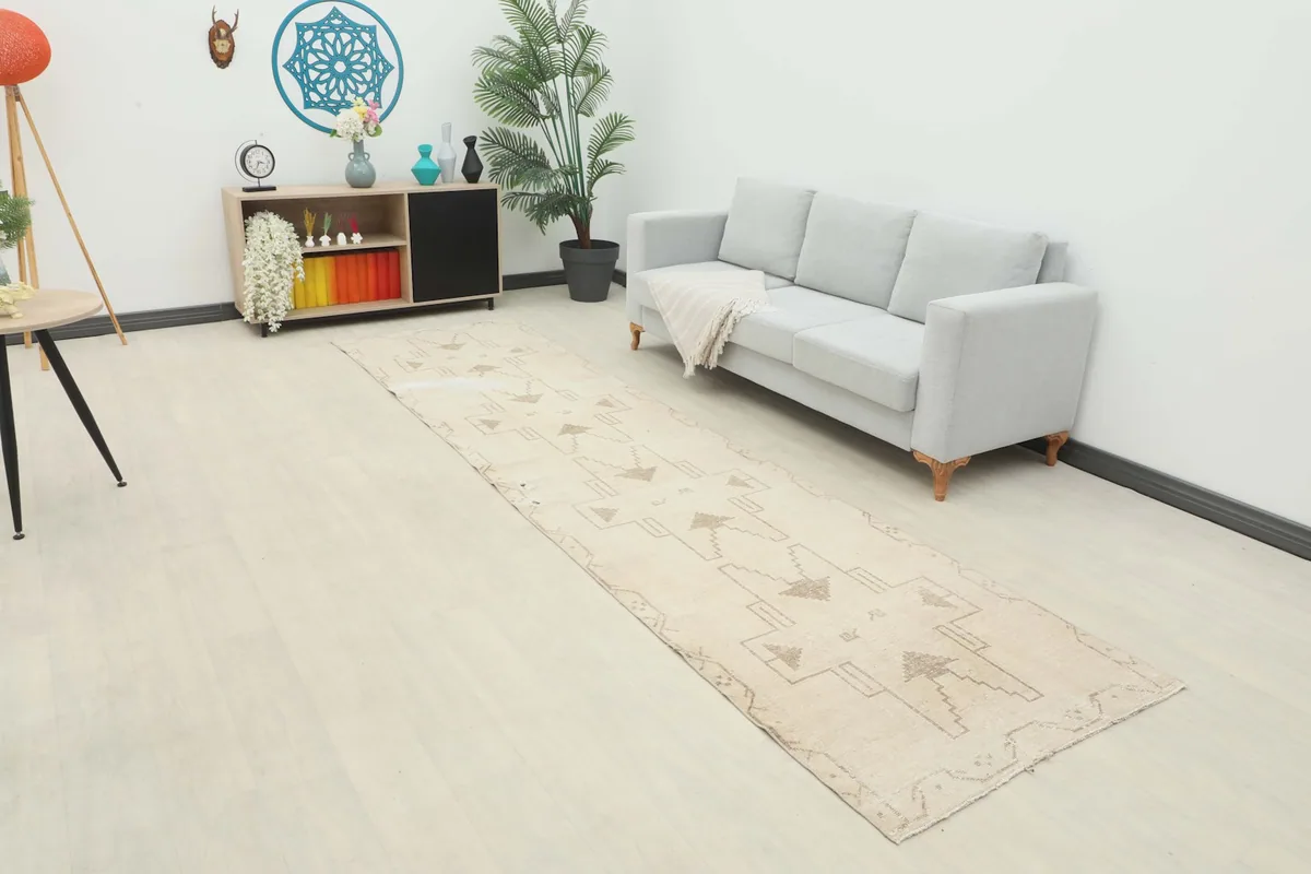 Ivory and tan runner rug laid out in a modern living space with a light gray sofa