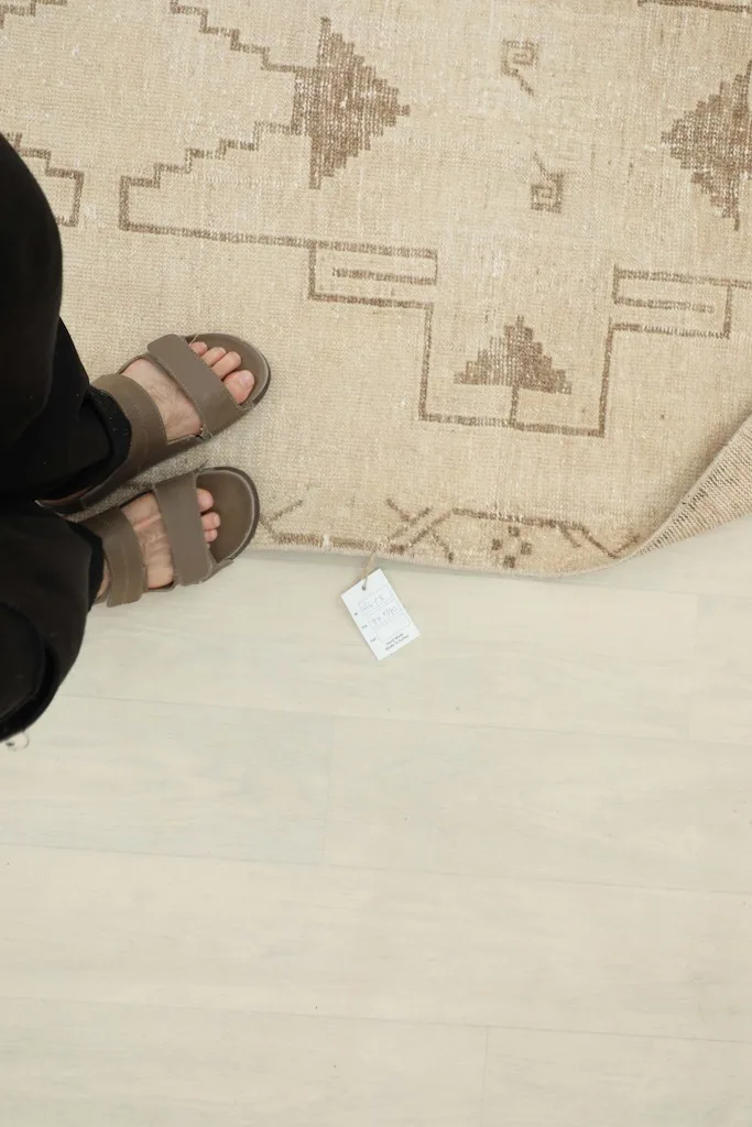 Overhead view showing feet on the rug next to a product tag for scale reference