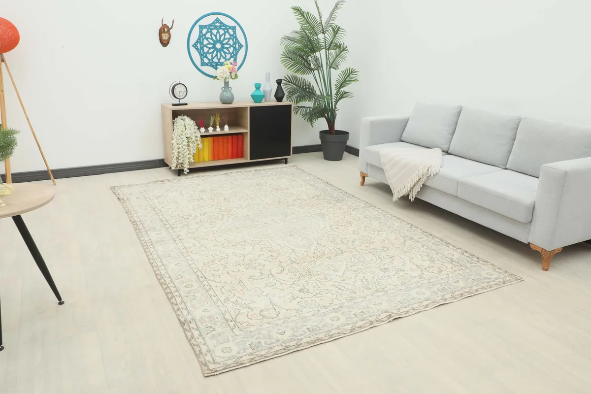 Vintage cream and blue rug displayed in a living room setting with a light gray couch