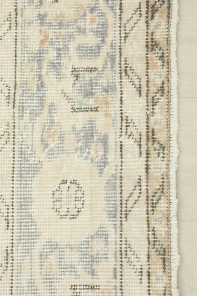 Edge of the rug showing the woven border pattern and the short, distressed fringe