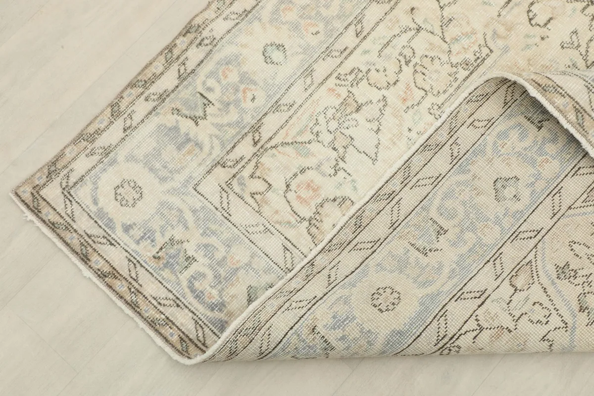 Corner of the rug folded, revealing the tight weave of the backing and border design