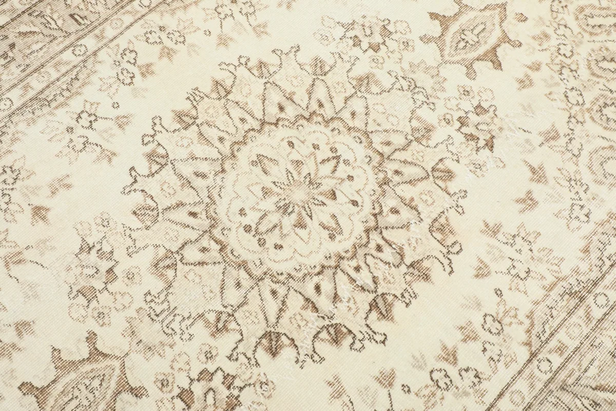 Detailed view of the central medallion design with beige and tan motifs on an ivory background.
