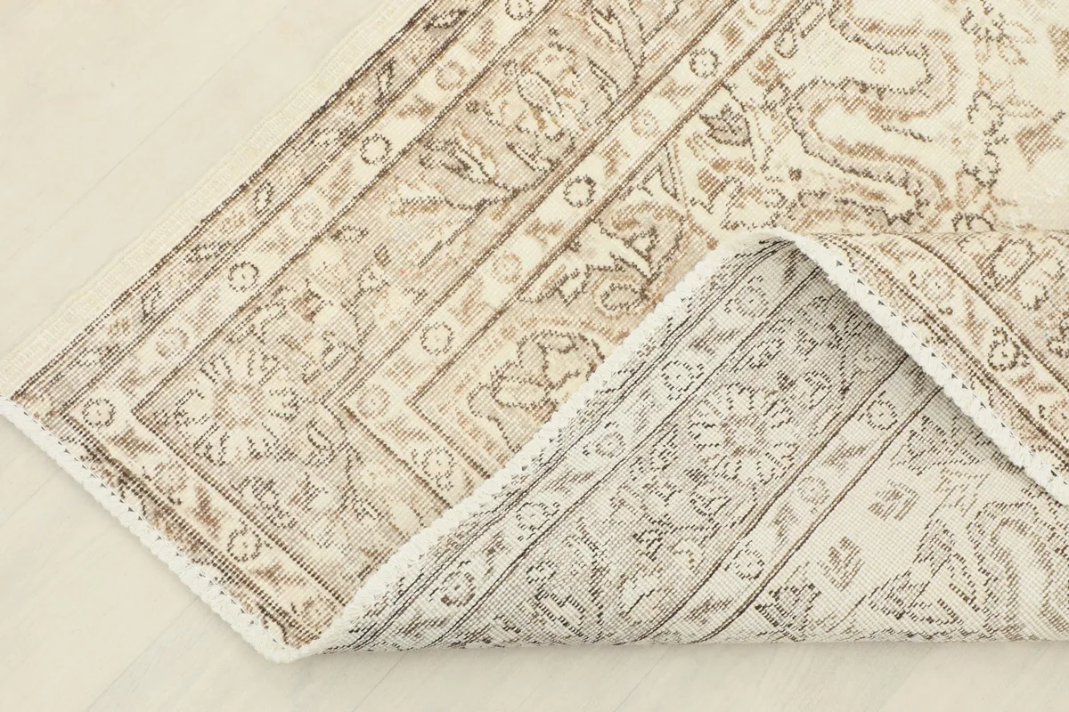 Corner of the rug folded back to show the reverse side and hand-knotted cotton foundation.