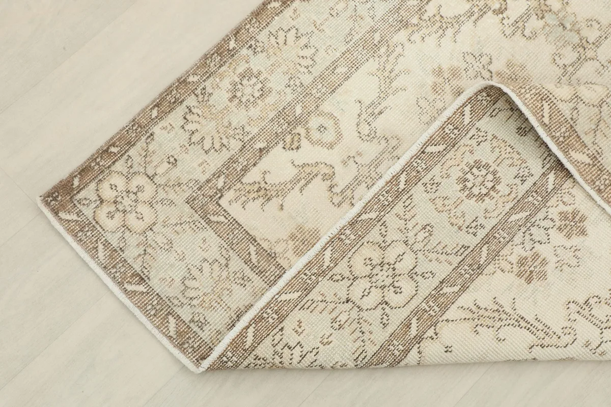 Corner of the rug folded back, revealing the reverse side and the cotton foundation