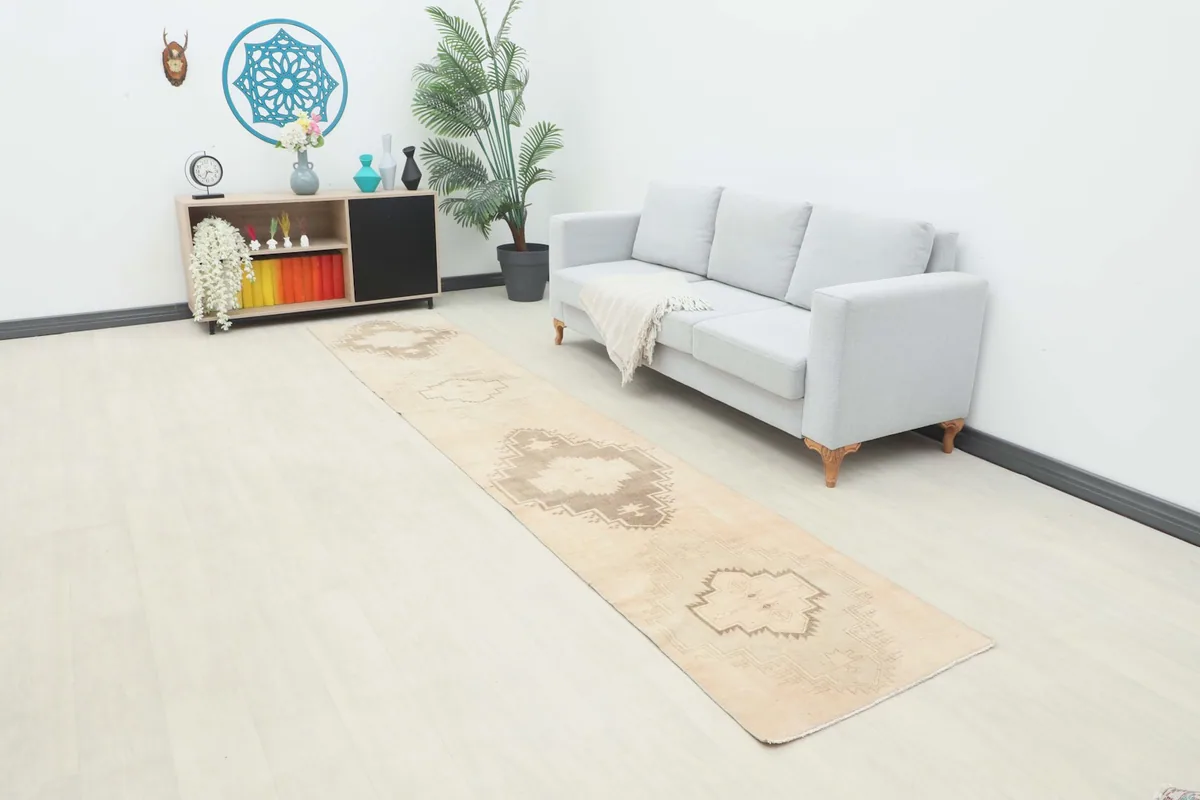 Wide shot of the entire runner rug laid out in a contemporary room setting with a sofa and shelf.
