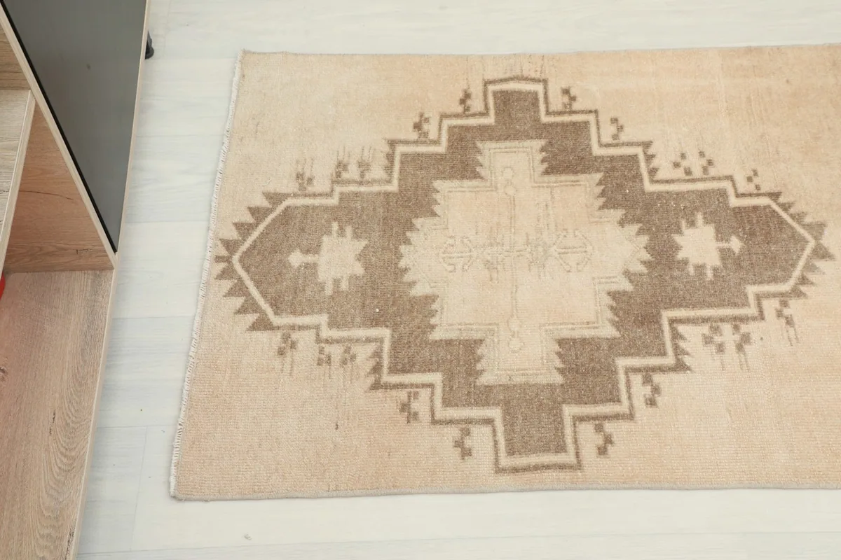Detailed view of a brown geometric medallion with beige accents on the rug.