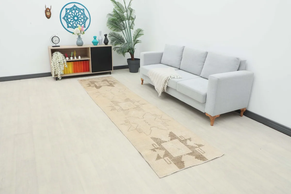 Vintage runner rug in an entryway or hallway setting with a light gray sofa and wooden cabinet