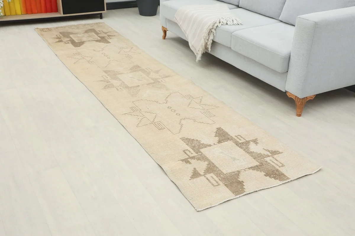 Angled view of the ivory and brown runner rug extending down a hallway next to a sofa