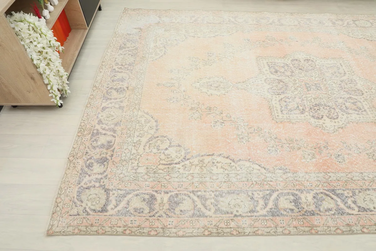 Corner view of the vintage rug, highlighting the muted colors and subtle wear on the rose and gray design.