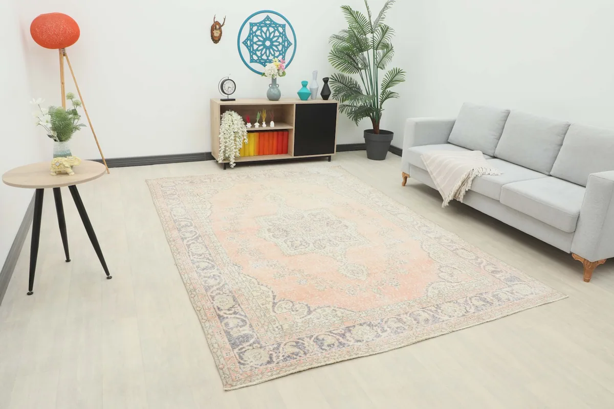 Vintage Anatolian rug displayed in a living room setting with a gray sofa and light wood furniture.