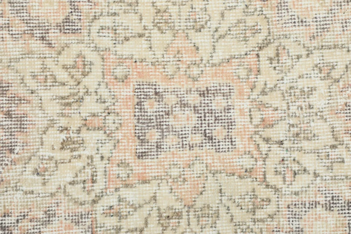 Close-up of the low wool pile, revealing the hand-knotted texture and the blend of rose, gray, and beige threads.