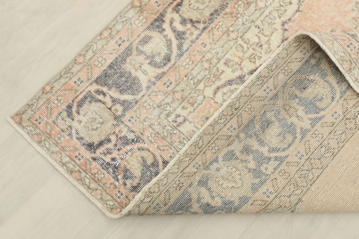 View of the rug folded, showing the cotton foundation and the reverse side of the hand-knotted wool pile.