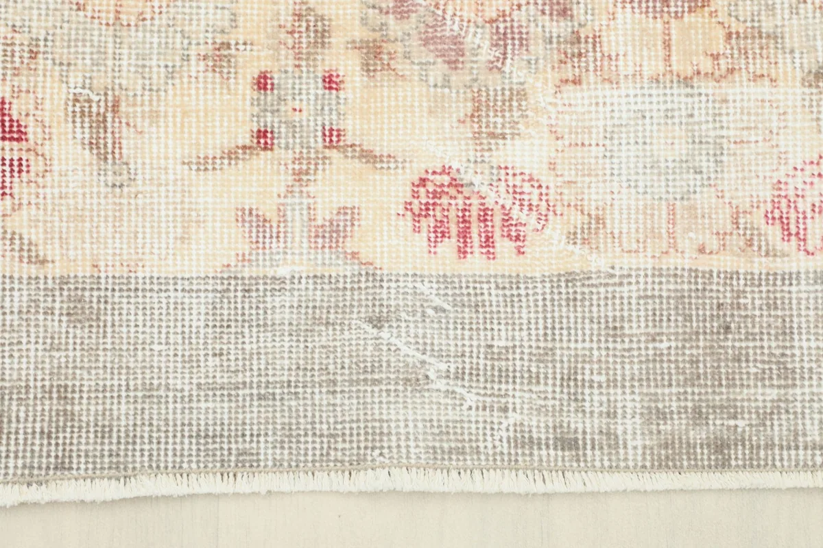 Detail of the rug's gray border and the transition to the cream field, showing slight wear.