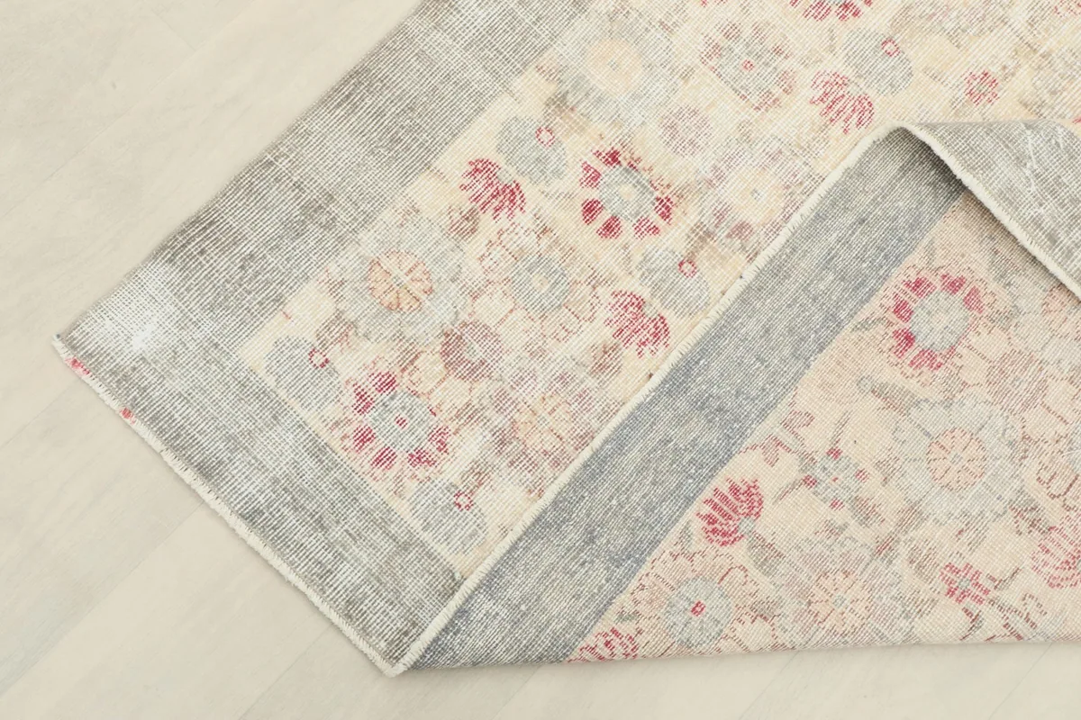 Corner of the rug folded back, showing the cotton foundation and the reverse side of the knots.