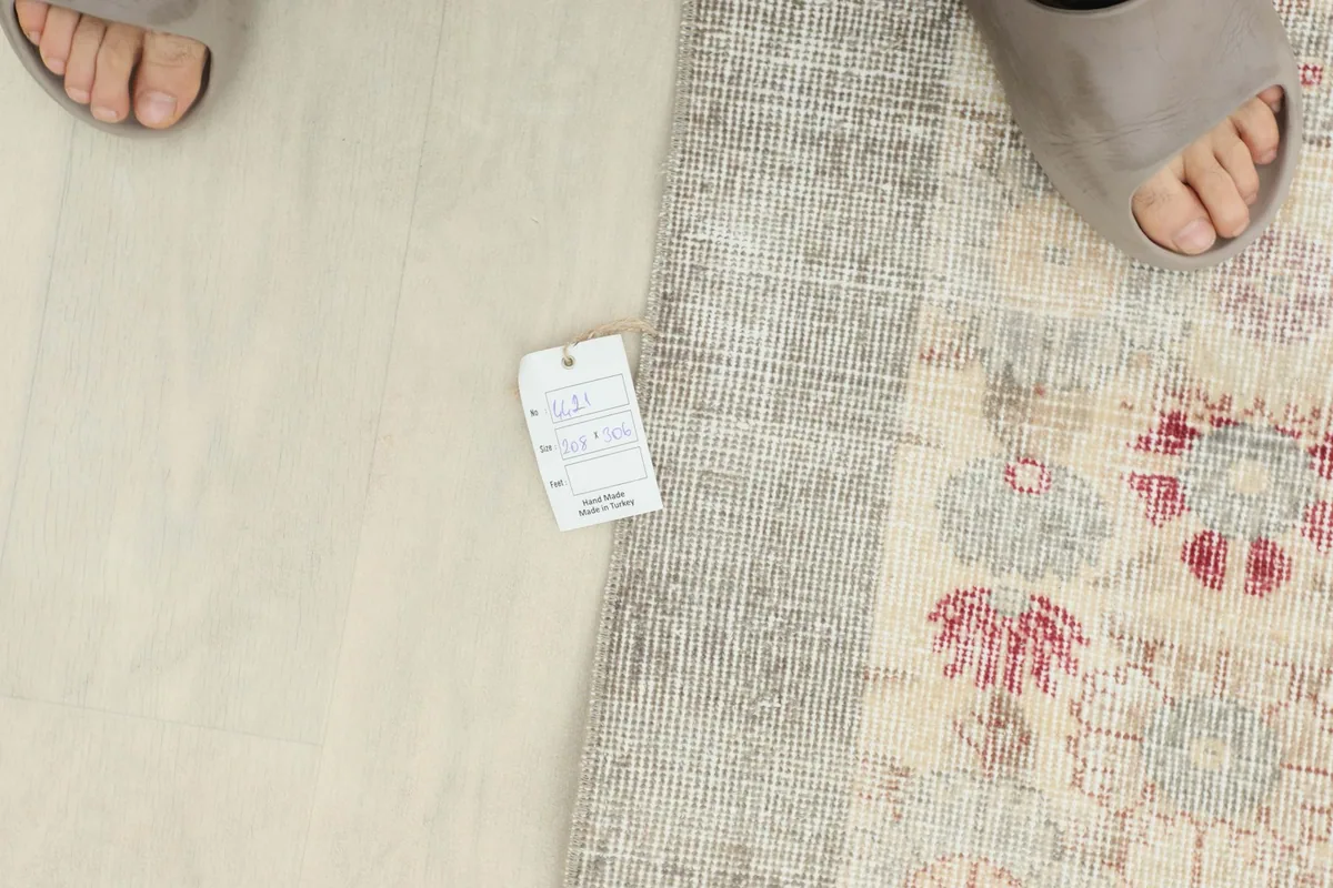 A person's feet next to a tag on the rug, showing scale and the low pile texture.