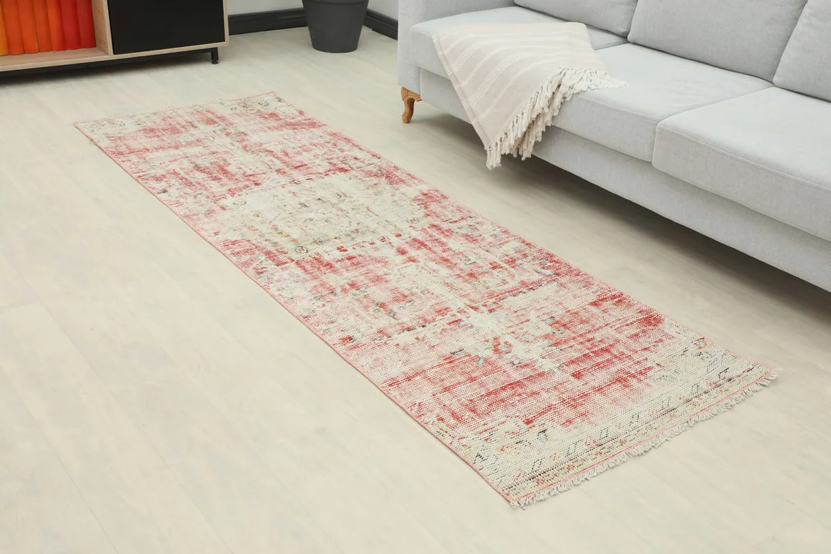 Angled view of the runner rug showing its length and distressed rose and cream pattern