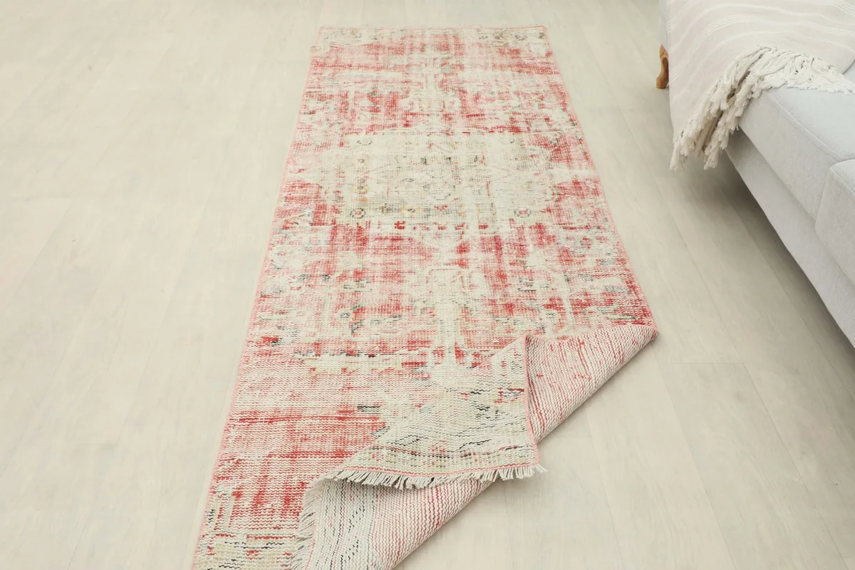 Runner rug partially folded in a room setting, providing a view of its underside and scale