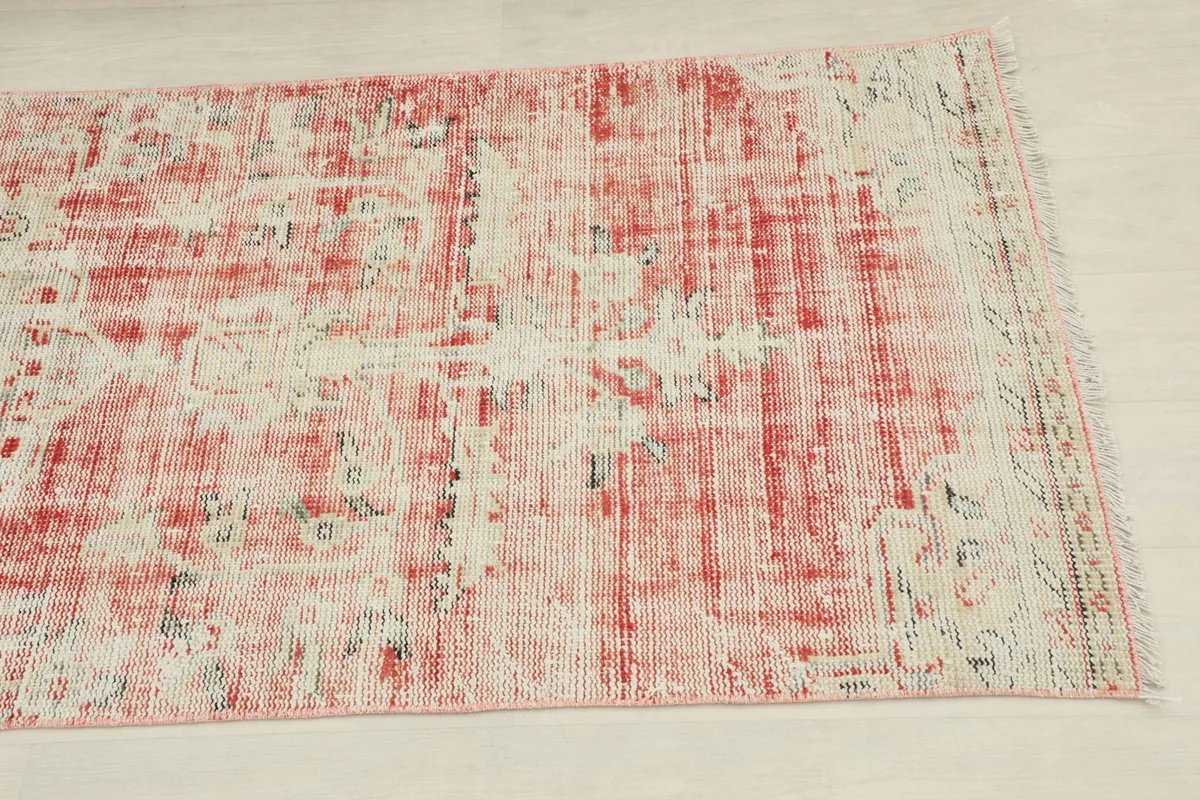 Close-up detail of the distressed rose field and cream geometric patterns on the rug
