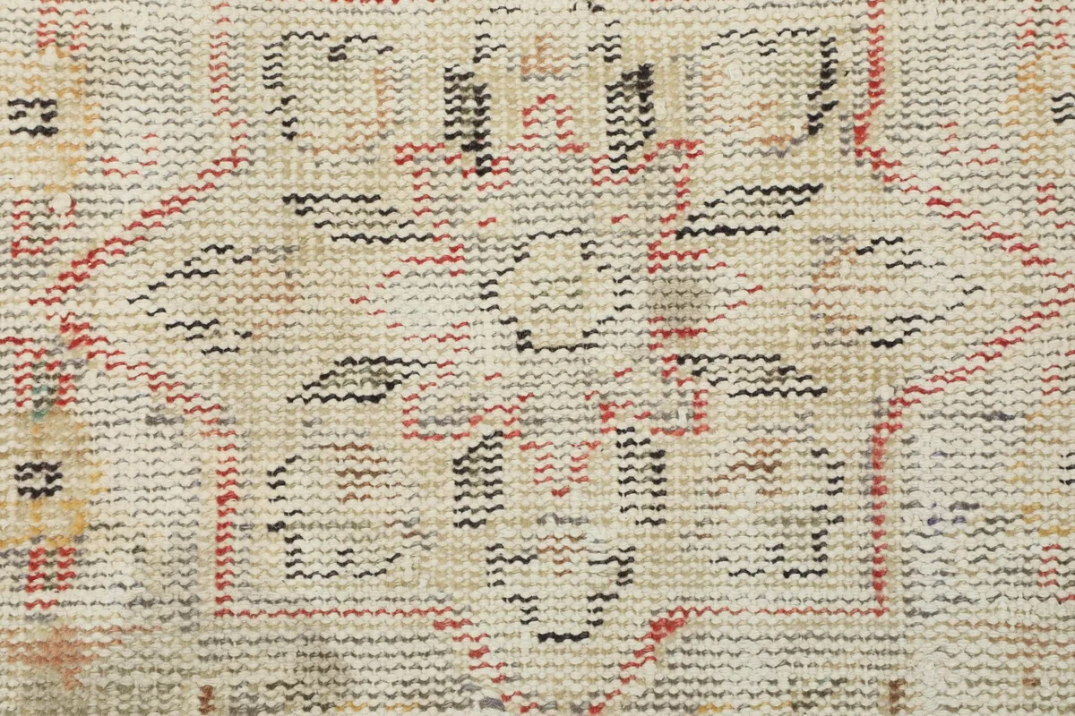 Extreme close-up of the low wool pile, revealing the knotting and texture of the vintage rug