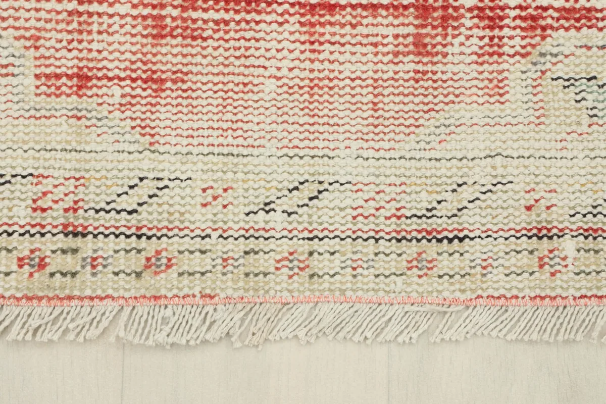 Detail of the rug's fringe and a section of the border, showcasing the cotton foundation