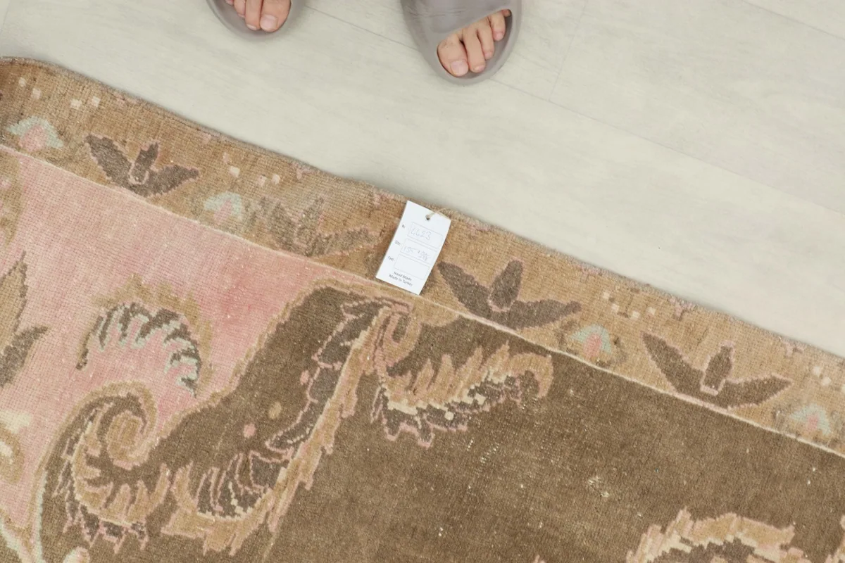 Overhead view showing the rug's tag and a foot in slippers for scale, emphasizing its authentic nature