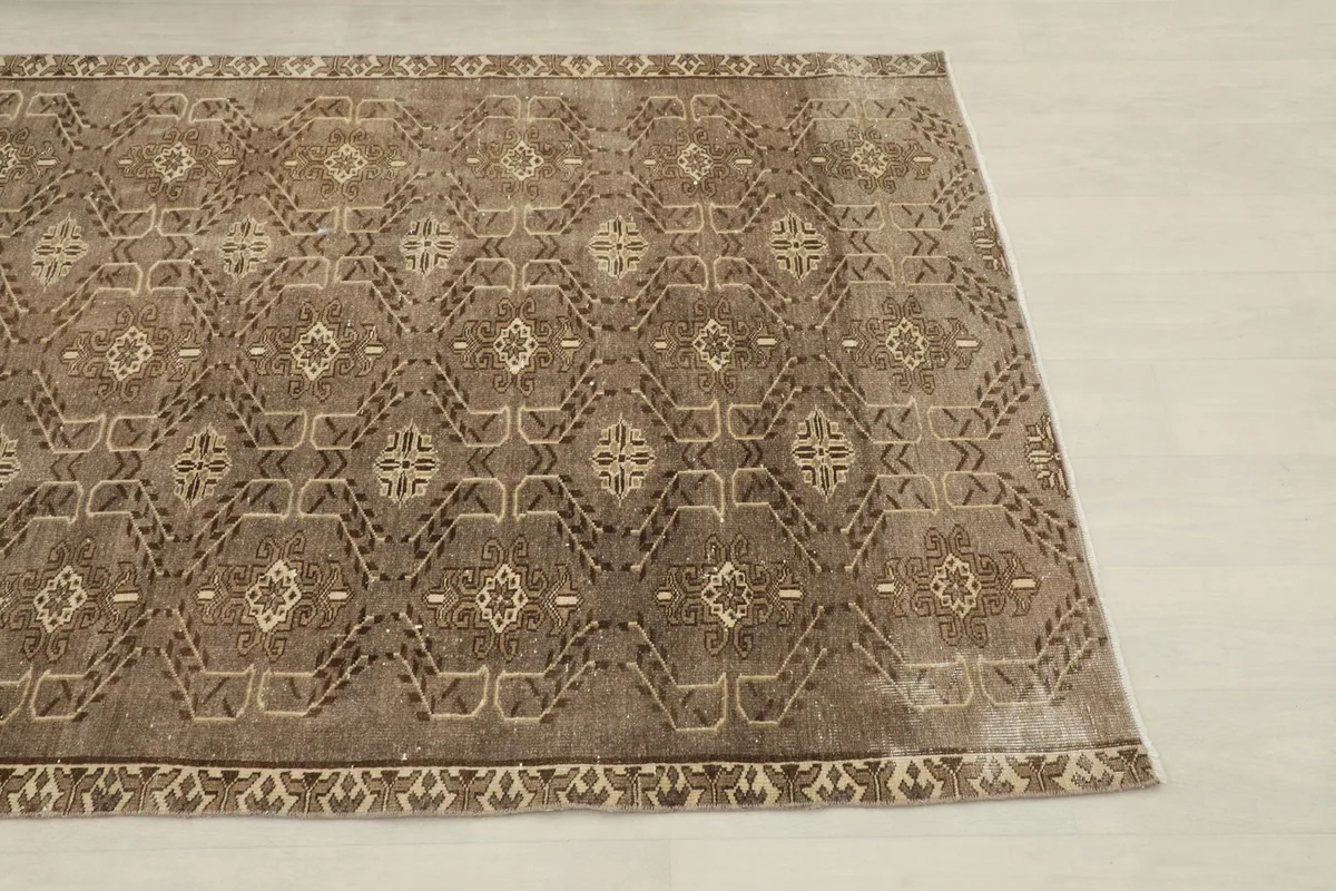 Close-up angle view of one end of the brown runner rug, showing the geometric patterns and border.