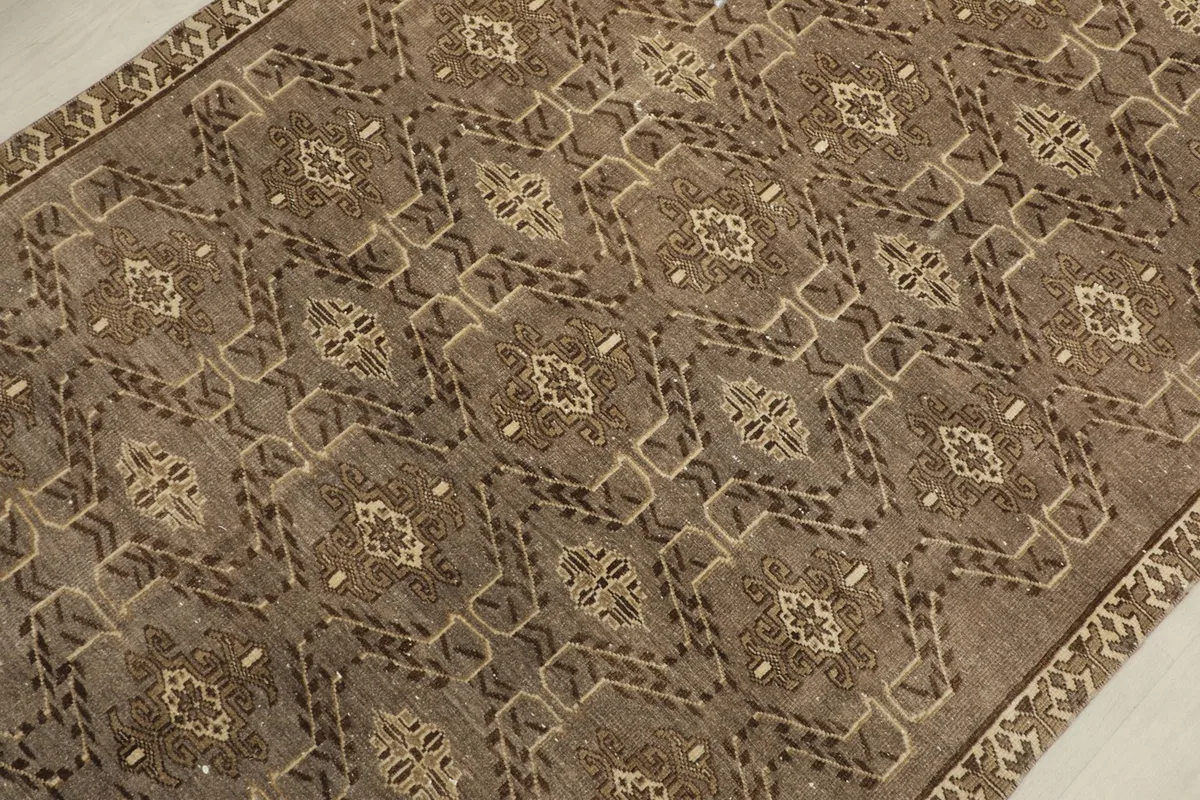 Detailed view of the brown and tan geometric motifs and the distressed texture of the rug pile.