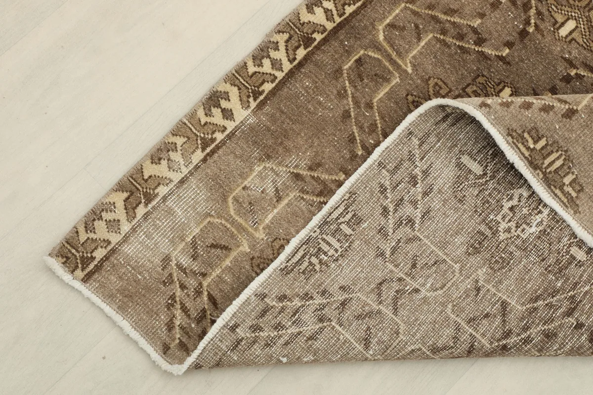 View of the underside of the hand-knotted rug, revealing the cotton foundation and a folded edge.