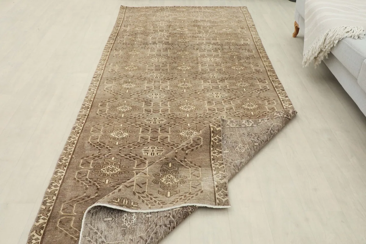 The runner rug partially folded back, showing the back of the rug and the distressed pile.