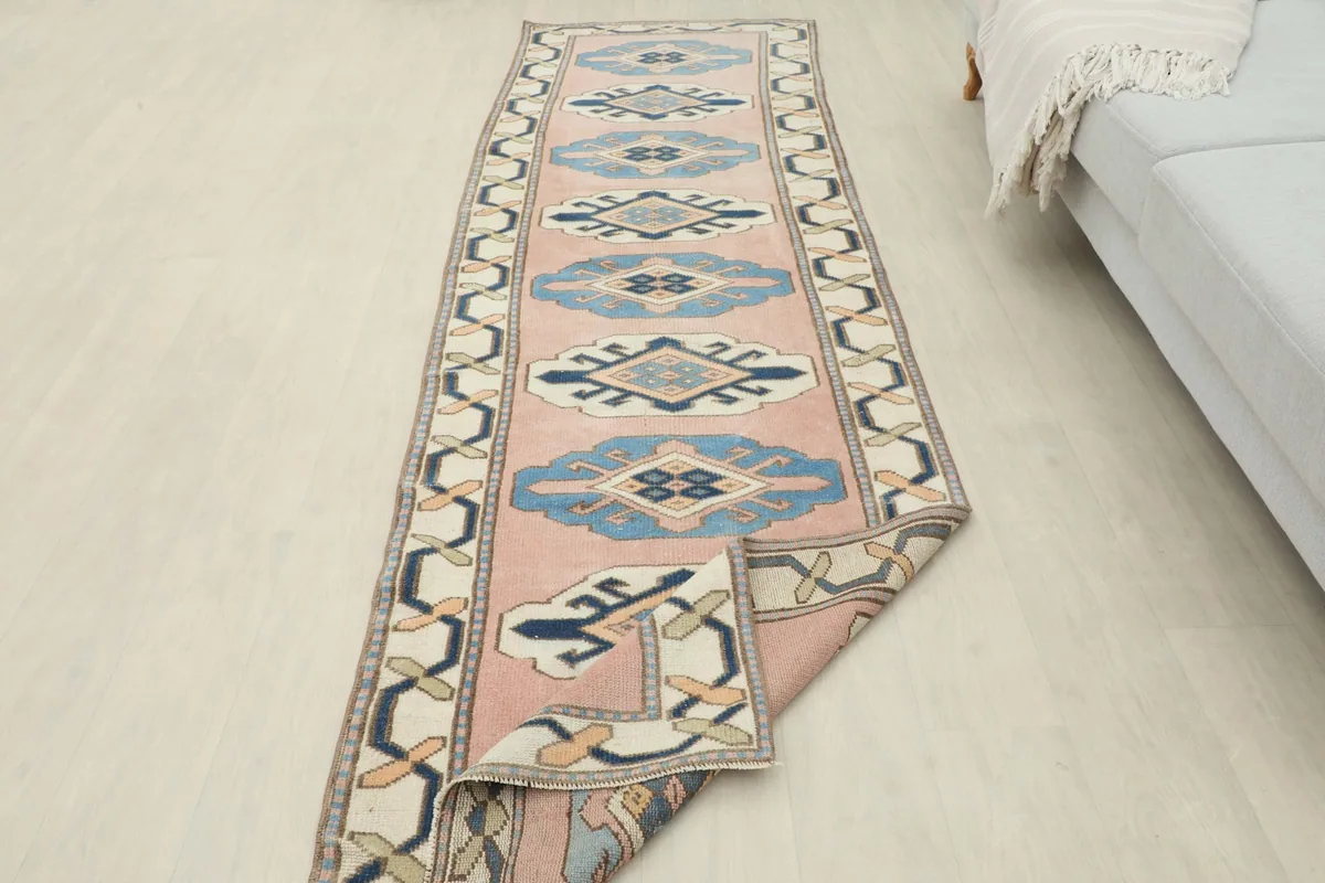 Long view of the pink and blue runner extending from a sofa into a room.