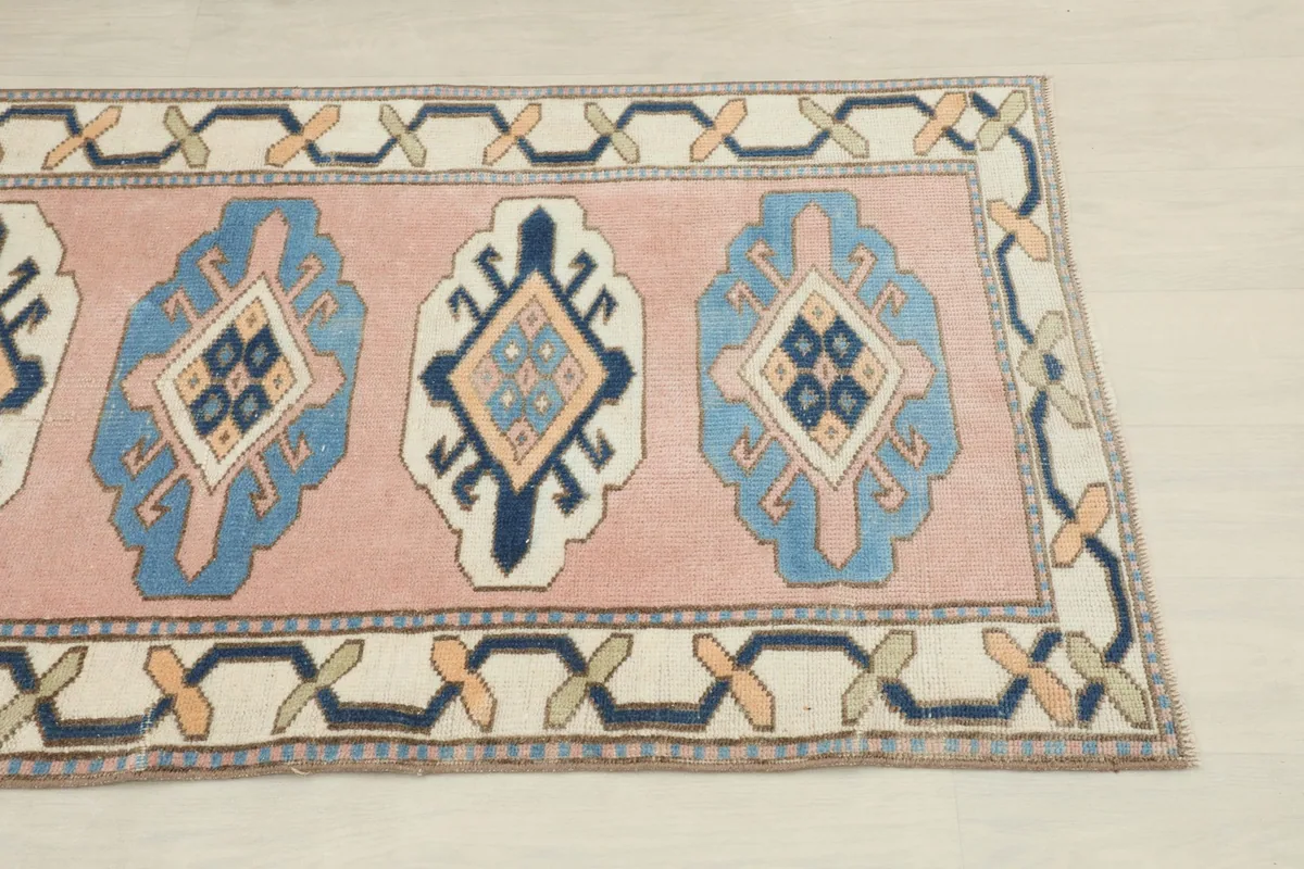 Close-up of the runner's end, highlighting the pink field, blue motifs, and ivory border.