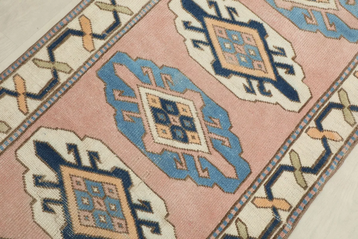 Detailed view of the central pink field and a blue geometric medallion with tan and navy accents.